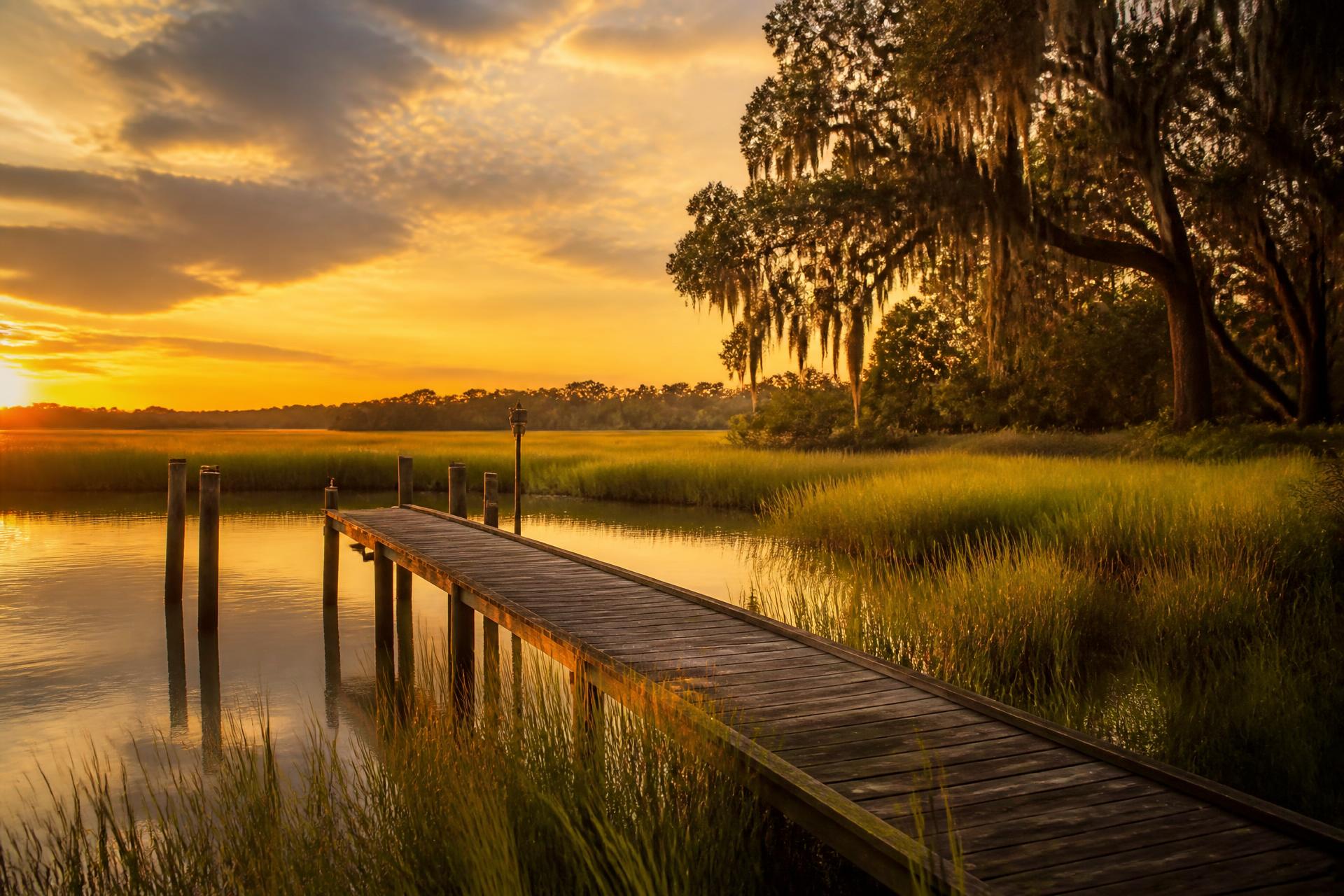 Wooden dock stretching into a South Carolina tidal marsh at golden hour